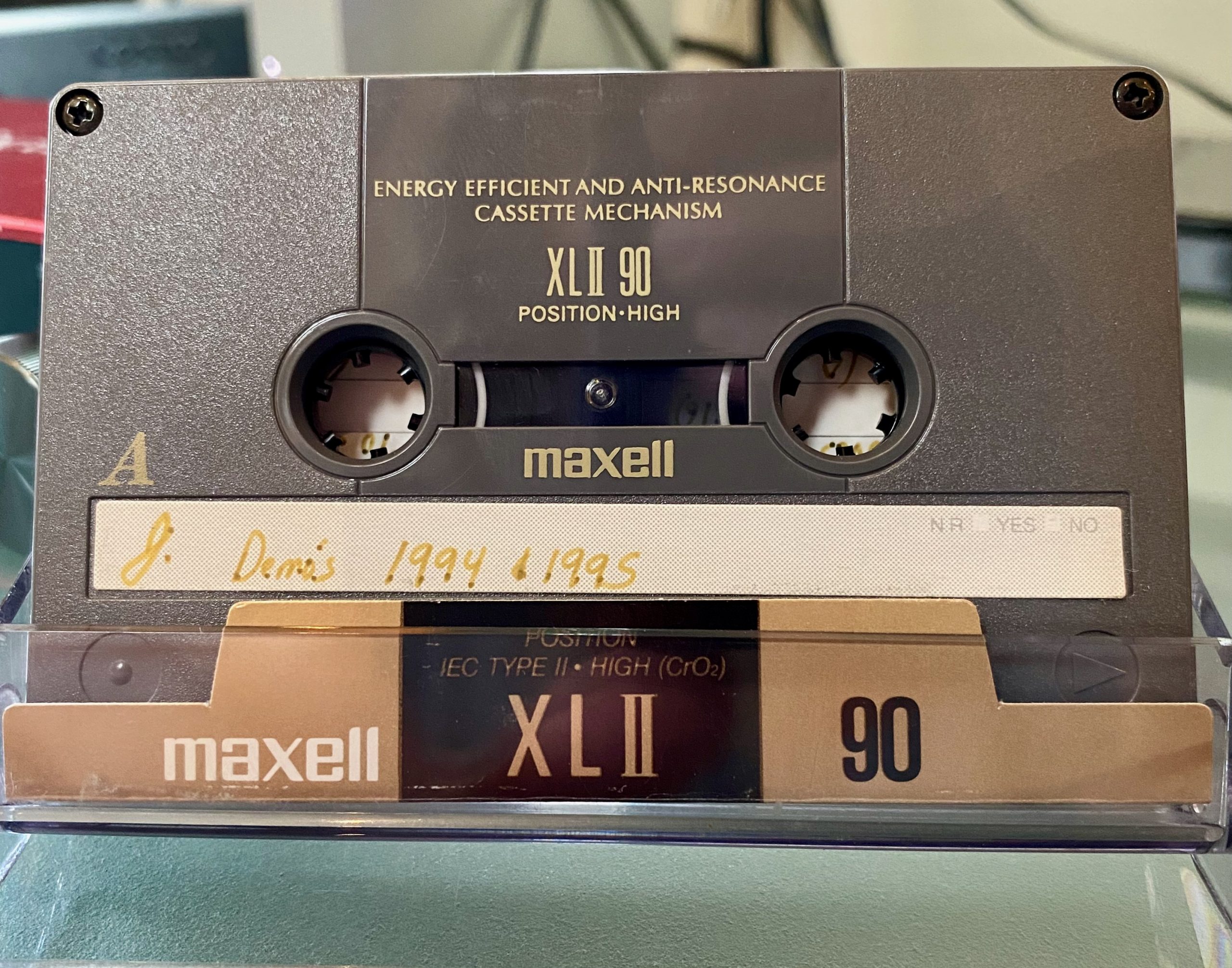 A Maxell XL-II cassette tape with the words "J's Demos 1994 + 1995" written on it with pen.